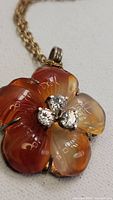 Close-up of the flower pendant showing carnelian agate petals and diamond-like stones in the center.