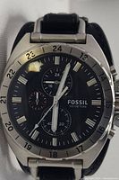 Front view of Fossil men's chronograph watch with black dial and beige markers, stainless steel case, black leather strap without buckle