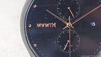 Close-up of Mvmt watch dial showing black face with rose gold markers and Mvmt logo