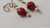 Close-up of the natural Japanese red coral and pearl bead earrings with gold-tone hooks, showing details of the coral's surface texture and coloration.
