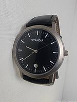 Front view of Scandia men's wristwatch showing black dial with silver markers and date window at 6 o'clock.