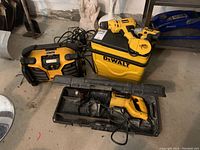 Photo showing DeWalt work site radio, cooler, two cordless drills with charger cables, all yellow and black color scheme, placed on floor.