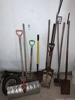 Full view of the gardening tools including snow shovel, shovels and wheelbarrow wheel.