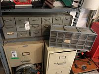 Metal and plastic hardware organizers shown on garage shelving with other storage items nearby, showcasing size and condition.