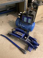Mastercraft air compressor with attached hydraulic floor jack and handle on concrete floor.