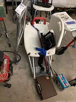 Overview showing bath chair, cane, electrodes, blood pressure monitor, walker, and gripper in garage setting.