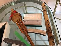 Top view of two harmonicas and two wooden flutes on a glass table.