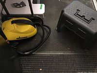 Yellow Wagner pressure washer and black resin tool caddy step stool beside each other on floor