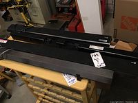 Photo showing four sound bars lying on a table in a storage or warehouse setting, including Sony, LG, and Samsung brands, as seen by brand logos on the fronts.