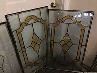 Two matching stained glass insert panels shown standing side by side with leaded geometric design in amber and clear glass.