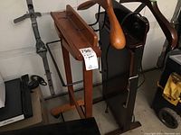 Photo showing two wooden suit valets side-by-side; one natural wood and one dark wood with heat pant presser.