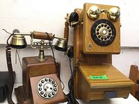 Pair of vintage-style rotary telephones made of wood and brass in a simple background