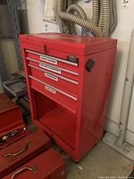 Front and side view of red Jobmate tool chest with labeled drawers for blades & scissors, drill bits & Allen keys, screwdrivers, and hand tools. Bottom compartment is empty.
