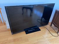 Front view of Sony Bravia TV on stand with remote placed on stand