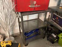 Front side view of metal utility cart showing two shelves and wheels; some surface wear visible.