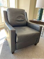 Front diagonal view of grey leather Bassett electric reclining chair showing cushioned seat, back, and armrests.