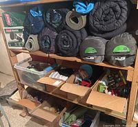 Shelf with rolled sleeping bags, self-inflating REI Camp Bed pads and plastic bins containing cooking gear and camping accessories