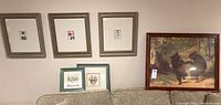 Three small framed botanical prints and one large framed wildlife print of bears above a couch