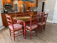 Three-quarter view of table and all six red ladderback chairs with striped cushions