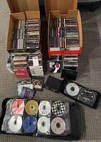 Photo showing a large number of rock and alternative CDs stacked in jewel cases, along with a binder containing CDs in sleeves and some loose cases.