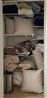 Closet shelf with various folded bedding, pillows, rolled textile, and towels
