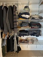 Overview of men's jackets and sweaters hanging on closet rod with folded clothing on shelves below including pants and shirts