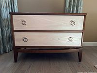 Front view showing two drawers with light-stained fronts and stainless steel ring knobs