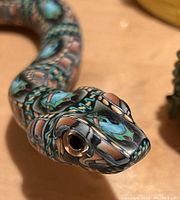 Close-up view of glass snake figurine head showing millefiori pattern