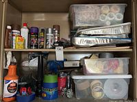 Wide view of the paint supplies and accessories stored on shelves including spray paints, adhesives, tapes, and trays.