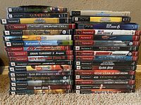 Photo showing stacked cases of about 36 PlayStation games including PSP, PS2, and PS3 titles.