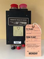 Front view of black rectangular avionics box labeled 'Remote Health Node', with red and pink electrical connectors and caution label.