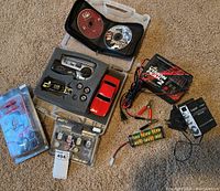 Overview of lot including RC car body, transmitter, Vision Peak 2 charger, Lepai amplifier, spare wheels, battery pack, and game discs