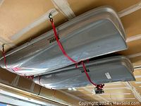 Side view of two Thule roof boxes strapped to garage ceiling