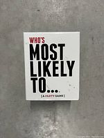 Front view of the white game box featuring the bold text 'WHO'S MOST LIKELY TO... [A PARTY GAME]' on a concrete surface.