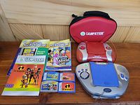 Two LeapFrog handheld education systems with games and guides displayed with a red carrying case.