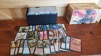 Large black box filled with over 500 Magic The Gathering cards, mostly uncommon rarity, displayed fanned out in front showing various card artworks and types.