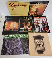 Photo showing front covers of all seven rock concert programs including Supertramp, Queen, Whitesnake, Kiss, The Who, Genesis, and Village People, arranged to display their cover art.