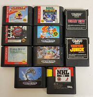Top-down view of all 10 game cartridges, 8 Sega Genesis and 2 ColecoVision, showing front label artwork and condition.