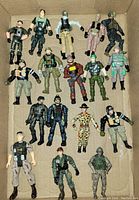 Full lot of 17 G.I. Joe action figures arranged in a cardboard box showing various military-style outfits and poses.