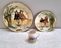 Front view of the two Royal Doulton Gallant Fishers plates showing illustrations of fishermen on a stone wall and a vintage Widecombe Pottery creamer pitcher.
