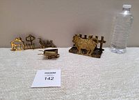 Full view of all three brass farm-themed items with water bottle for size reference, including cow napkin holder, duck wall hook, and mini wheelbarrow.