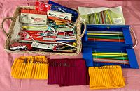 Overview photo showing basket filled with various knitting needles, crochet hooks, knitting needle storage cases, and sewing kits.