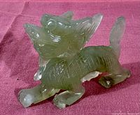 Side view of the green jade carved Chinese dragon sculpture showing detailed scales and curled tail.