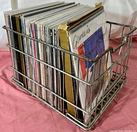 Metal wire milk crate filled with vinyl LP albums seen from a side angle