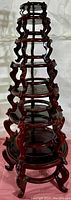 View showing the six wood stands stacked together to display their graduated sizes and intricate leg detailing, glossy lacquer finish visible