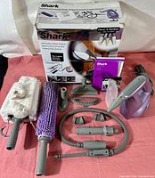 Photo showing the complete steam cleaning system with handheld unit, wands, cleaning pockets, nozzle attachments, instruction manuals, and original box.