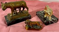 Set of three vintage figural paperweights with Remus and Romulus statue on marble base, bronze lion on marble base, and cast copper lion figurine.