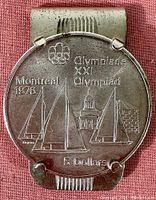 Front view of the sterling silver money clip displaying the attached 5 dollar coin with sailboats and buildings under the Olympic rings for Montreal Olympiad XXI 1976.