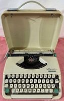 Full view of Olympia Splendid 33 typewriter inside open cream metal case showing keyboard and body