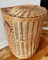 Side view of basket showing half-circle half-oval shape and woven wicker handles on the side.